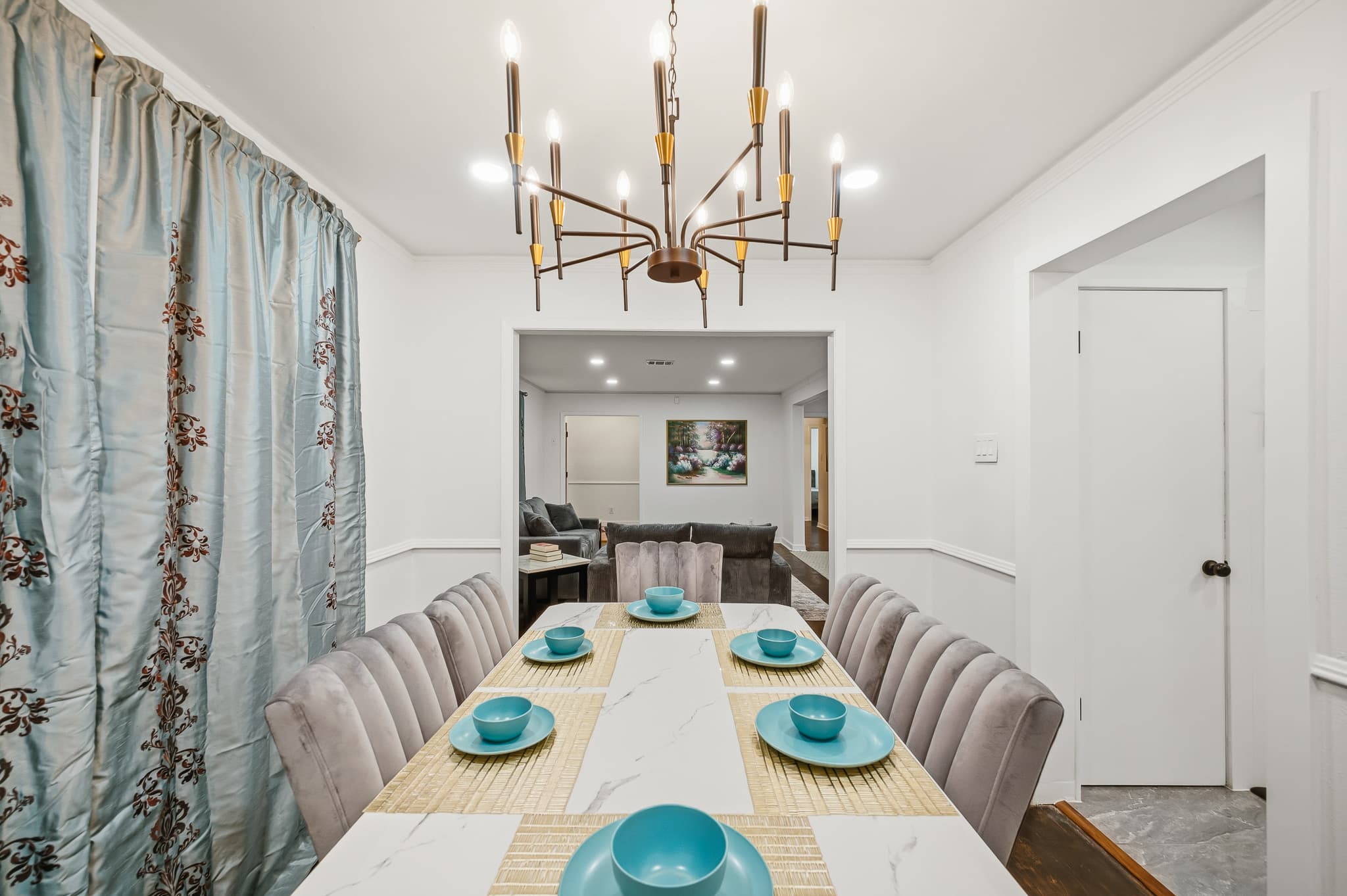 Dining table set for six beneath a brass chandelier